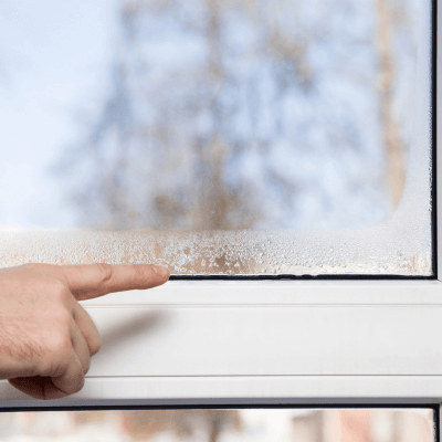 finger pointing at moisture on window to check for mold