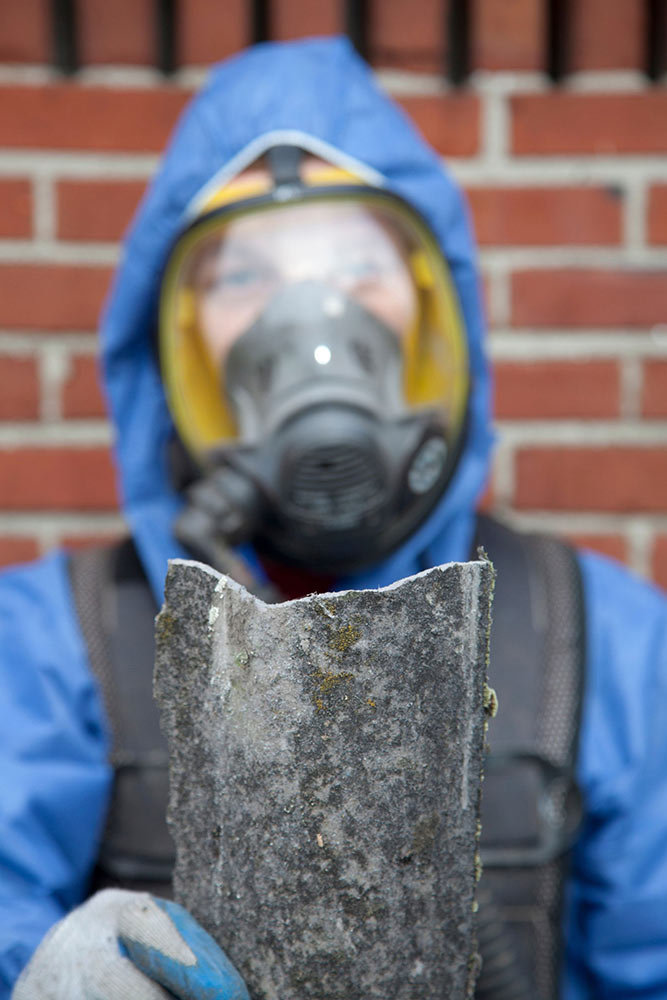 Man in hazmat suit holding asbestos material