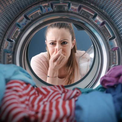 woman holding nose washing machine stinks moldy washer